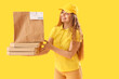 © Pixel-Shot - Female courier with paper bag and pizza boxes on yellow background