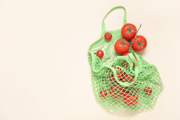 Wall Mural - Mesh bag with fresh tomatoes on beige background