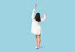 © Pixel-Shot - Young woman in stylish white dress dancing on blue background, back view