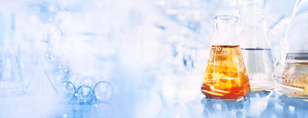 Wall Mural - orange solution in flask and test tube in science research lab with blue banner background