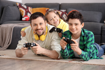 Canvas Print - Happy father with his little children playing video game on floor at home