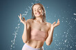 © Pixel-Shot - Young woman with splash of water on blue background