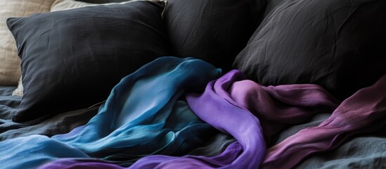 Poster - Elegant arrangement of colorful silk scarves draped over dark pillows on a textured bedspread Copy Space