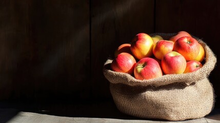 Poster - Fresh red apples in a jute bag with natural light highlighting the texture and colors isolated on wooden background Copy Space