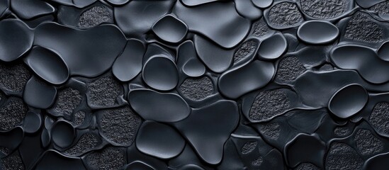 Poster - Abstract textured background of smooth black pebbles with varying shapes and sizes on a dark surface Copy Space