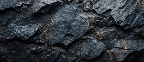 Poster - Texture of natural dark slate stone wall with irregular surfaces and shadows ideal for backgrounds or design projects with Copy Space.