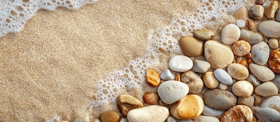 Poster - Sandy beach with smooth colorful stones and foamy waves creating a natural coastline texture Copy Space