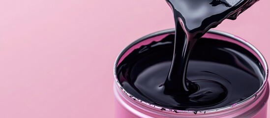 Poster - black glossy paint pouring from a container on a pink background with copy space for text