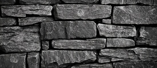 Poster - Black and white textured stone wall with irregularly shaped slabs stacked together and visible mortar joints Copy Space