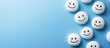 © pngking - White smiley faces scattered on a vibrant blue background, evoking happiness and positivity, with ample empty space for text placement.