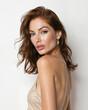 © Lidia - Close-up portrait of a young woman with shoulder-length auburn hair, soft glowing skin, and a confident expression, wearing a simple beige satin dress, against a neutral light-colored background, exud
