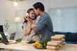 © crizzystudio - Young asian couple embracing and listening to music with headphones while preparing fresh vegetables for a healthy meal in a modern kitchen