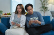 © crizzystudio - Young asian couple sitting on sofa counting dollar banknotes at home, managing family budget, planning investments, paying bills, calculating expenses, or enjoying financial success