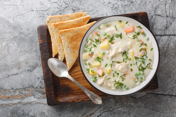 Wall Mural - Comfort chicken pot pie soup with potatoes, carrots and green peas in a spicy creamy broth close-up in a bowl on the table. Horizontal top view from above