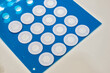 © Igor - White circular adhesive patches on a blue sheet, designed for sealing, filtration, or protective purposes. Clean and uniform layout.