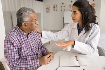 Emotional support. Caring young female doctor nurse medical worker hold hand on elderly male shoulder give psychological assistance to worried scared patient help to accept diagnosis express empathy