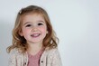 © Юля Бурмистрова - Joyful child with curly hair smiles brightly against a clean white background, showcasing innocence and happiness in a professional studio setting