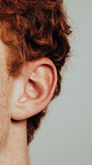 Poster - Redhead man's ear is examined closely, highlighting potential hearing problems and emphasizing the importance of ear care and seeking medical attention for hearing loss