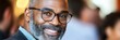 © Ilja - Confident Mature Professional Headshot of a Smiling Black Businessman in a Blurred Office Setting