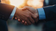 © NaphakStudio - close up of two hands shaking, symbolizing partnership and agreement in professional setting. warm sunset adds positive atmosphere.