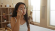 © Krakenimages.com - Young chinese woman indoors at a spa wellness center, applying skincare in a serene and well-lit beauty room.