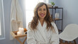 © Krakenimages.com - Smiling woman in white bathrobe sitting in a serene spa environment with lit candles and comfortable decor