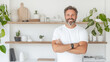 © Number One Studio - smiling man stands confidently in modern, bright room filled with plants and decorative items on shelves. atmosphere is inviting and stylish, showcasing contemporary lifestyle