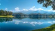 © Danila - Tranquil lake view flanked by lush summer foliage under a sky of clear blue with white clouds