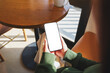 © Farknot Architect - Mockup image of a woman holding mobile phone with blank desktop screen in cafe