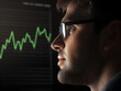 © Zape - A businessman looking at a digital screen displaying market data, with glowing upward trends in assets.