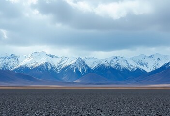 Snow capped mountains behind rocky landscape and cloudy sky