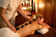 © InfiniteFlow - Hot stone massage at spa salon in luxury resort with warm candle light, blissful woman customer enjoying spa basalt stone massage glide over body with soothing warmth. Quiescent