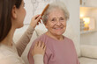 © New Africa - Granddaughter brushing her grandmother with comb at home, selective focus. Elderly care