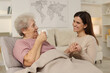 © New Africa - Grandmother with hot drink and her granddaughter at home. Elderly care