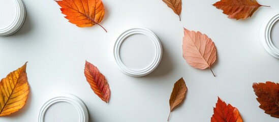 Poster - Autumn leaves scattered with white circular paint cans on a light background featuring ample Copy Space for text placement.
