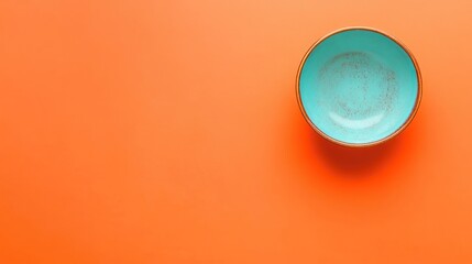 Poster - Turquoise ceramic bowl on vibrant orange background with Copy Space for text placement