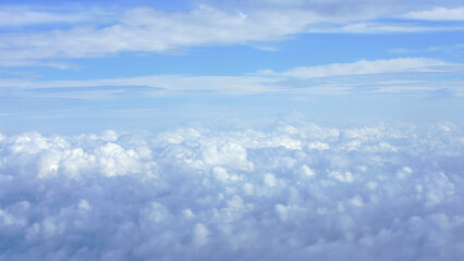 Wall Mural - Aerial view of fluffy white clouds with a hint of Earth horizon during a flight