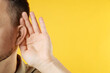 © New Africa - Man showing hand to ear gesture on orange background, closeup. Space for text