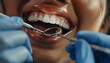© Asad - Close-up of a smiling black woman patient during a dental examination, with a dentist using a mirror and scaler for oral care, highlighting clean and healthy teeth.
