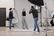 © New Africa - Photographer and assistant working with model in professional photo studio