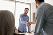 © fizkes - Young businessman greeting new team member, client, or partner, shake hands gathered in boardroom, showing acknowledgment and respect, confirming commercial deal, partnership, or mutual understanding