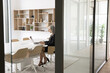 © fizkes - In modern spacious conference room middle-aged 55s businesswoman using laptop, lead correspondence to client, chatting with colleague, e-mailing, looking focused and productive. Business, workflow