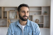 © fizkes - Thoughtful Hispanic freelancer, man posing indoors, smile, looking out window with optimistic expression, feels self-assured, satisfied with project completion, perspectives and business opportunities