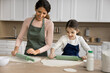 © fizkes - Funny cooking. Little preteen age girl daughter engaged in doing household chores with young mom babysitter in form of game enjoy rolling dough competition learn baking pie imitate mother at kitchen