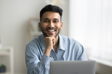 Wall Mural - Success in profession. Portrait happy smiling young man office worker freelancer sit at workplace by notebook. Friendly male consultant advisor insurer look at camera feel satisfied glad enjoy his job