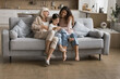© fizkes - Carefree weekend. Laughing 3 generation family tickle on couch joyful elderly mum grandma playing messing on sofa with young adult daughter preteen girl grandkid having fun enjoy leisure time together