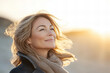 © MashMash - Serene middle-aged woman enjoying a peaceful moment on a sunny beach with ocean waves in the background, showcasing natural beauty, relaxation, and carefree emotions for lifestyle, travel, and wellnes