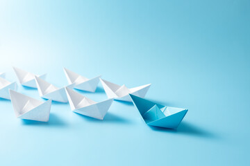 Leadership concept with blue paper ship leading among white