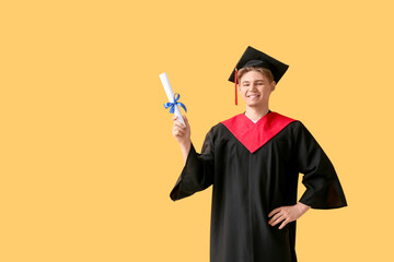 Wall Mural - Happy male graduate with diploma on yellow background