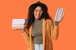 © Pixel-Shot - Beautiful young African-American woman with stacks of books on orange background
